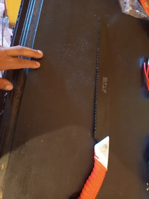 Қызыл тұтқасы мен қисық жүзді пышақ ағаш бетінде