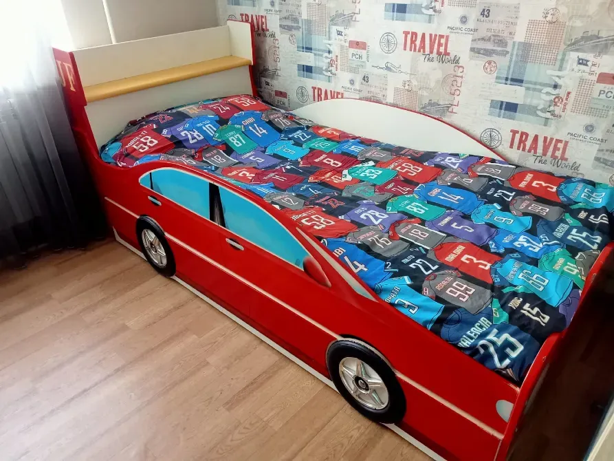 Қызыл машина түріндегі жатағы бар, түрлі-түсті жапқышы мен саяхат стиліндегі қабырғалары