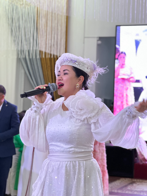 Певица в белом платье с микрофоном на праздничном вечере