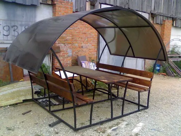 Просторный металлический навес с деревянным столом и скамейками