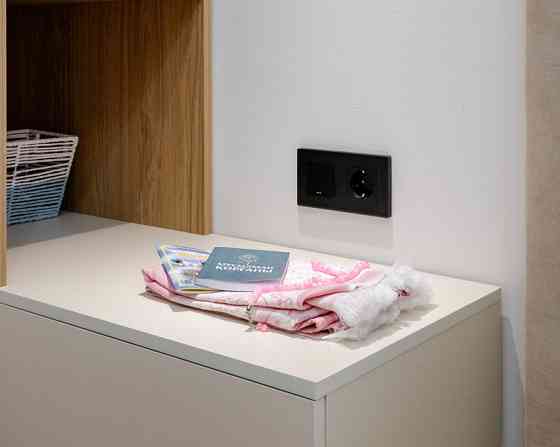 Столик с книгами и пледом на белом столе рядом с электроприбором