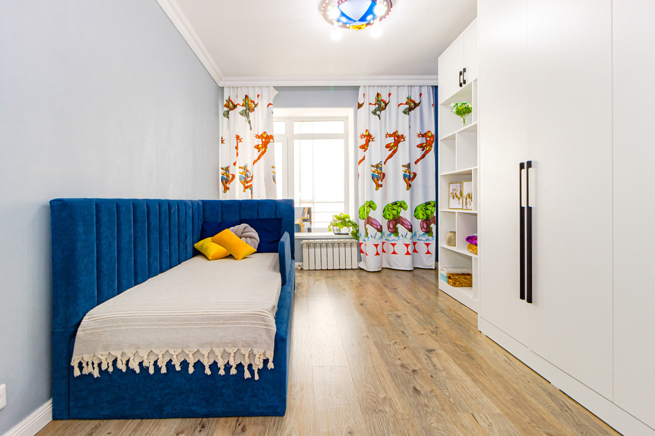 Детская комната с синим диваном и яркими шторами