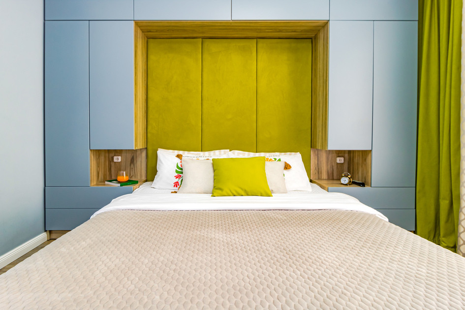 Детали спальни с кроватью и зеленым акцентом на стене