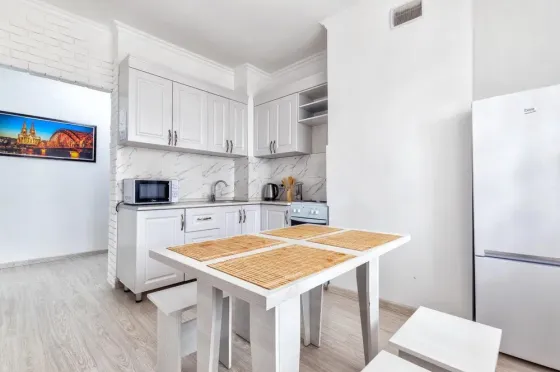 Современная кухня с белыми шкафами и обеденным столом