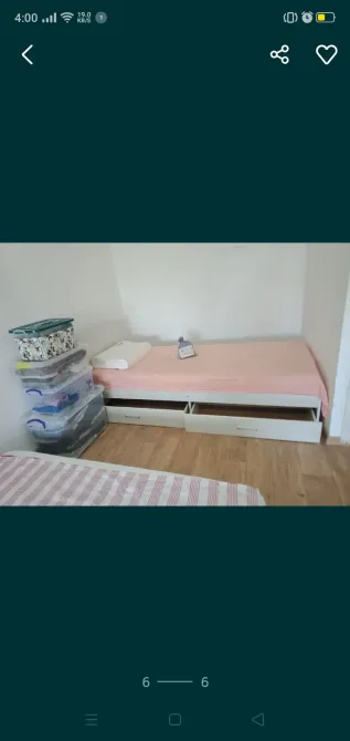 Кровать с розовым матрасом и ящиками внизу в комнате с деревянным полом