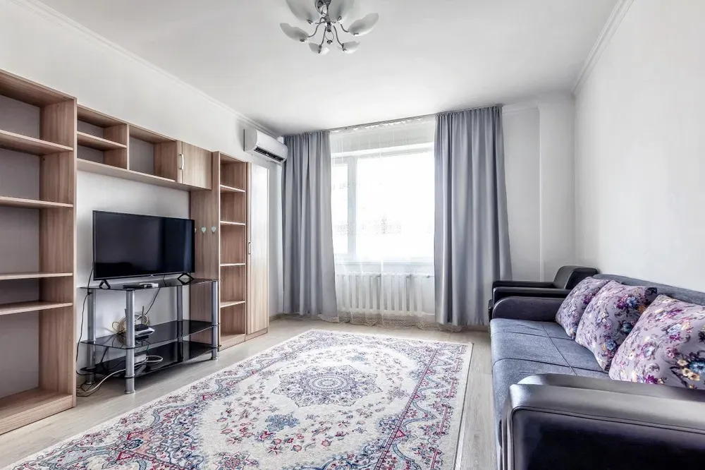 Гостиная с телевизором, диваном и декоративным ковром