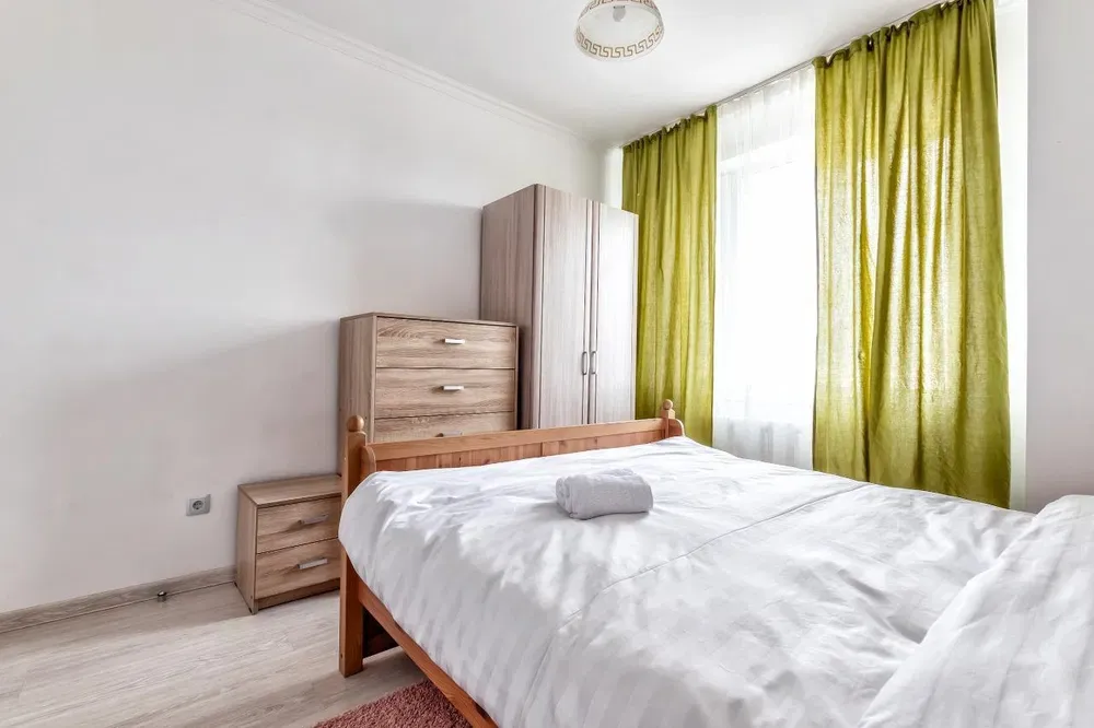 Уютная спальня с двуспальной кроватью и зелеными шторами