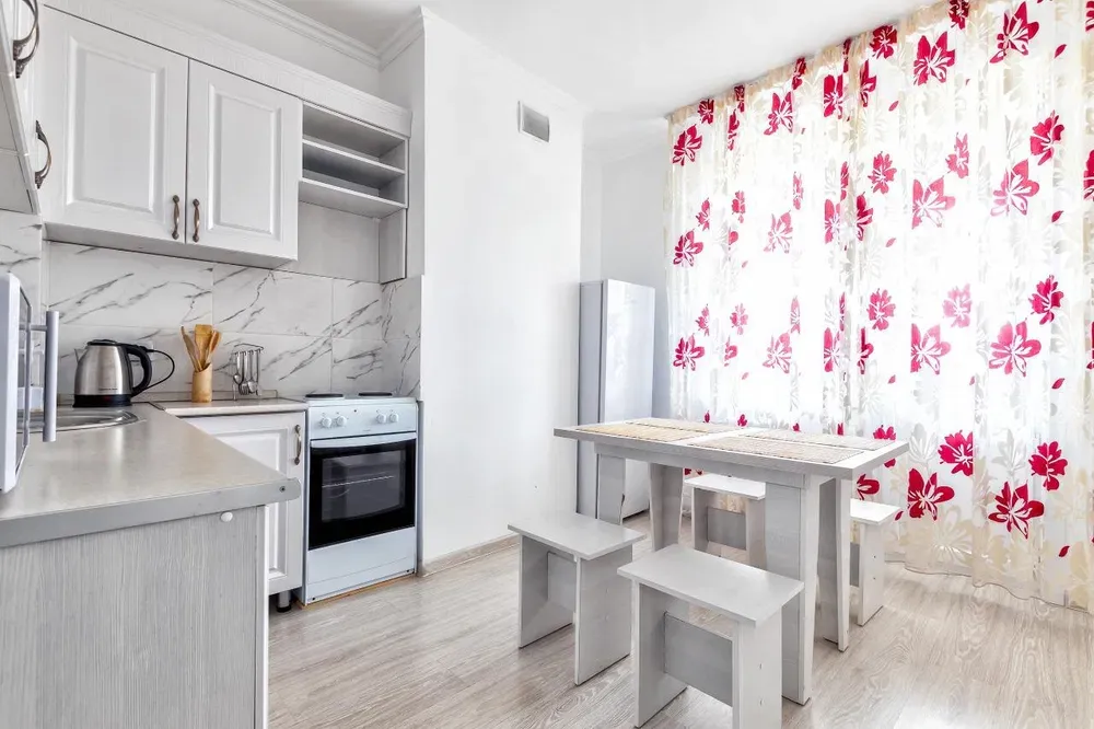 Просторная кухня с обеденным столом и яркими занавесками