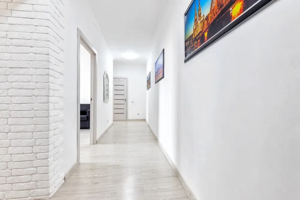 Длинный коридор с белыми стенами и картинами