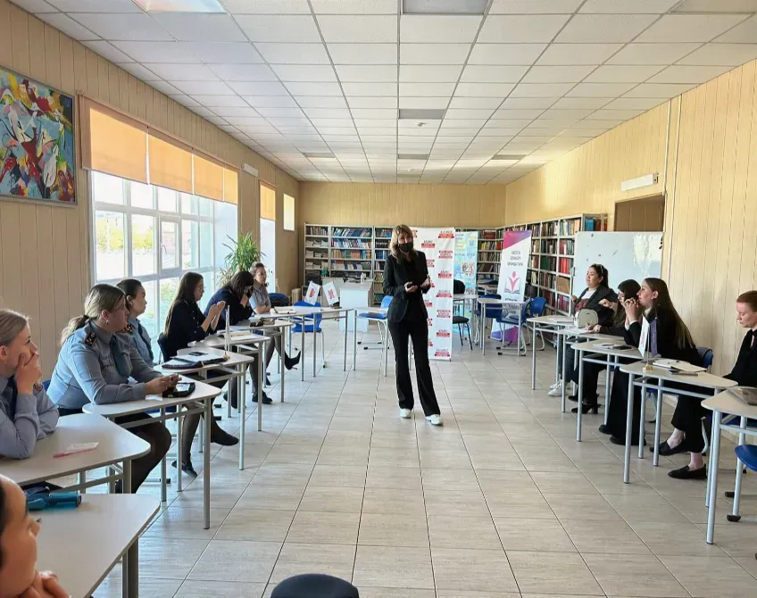 Оқушылармен сыныпта топқа сабақ өткізіп жатқан әйел.