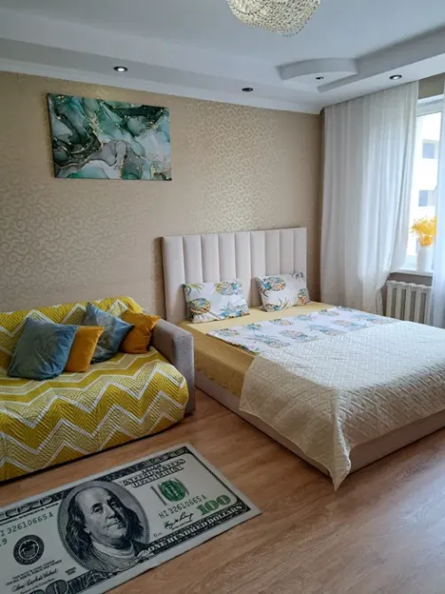 Спальня с желтым покрывалом и диваном, украшенная картиной