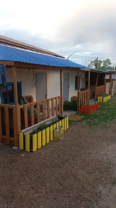 Веранда мен түрлі-түсті гүлзарлары бар ғимараттың көрінісі