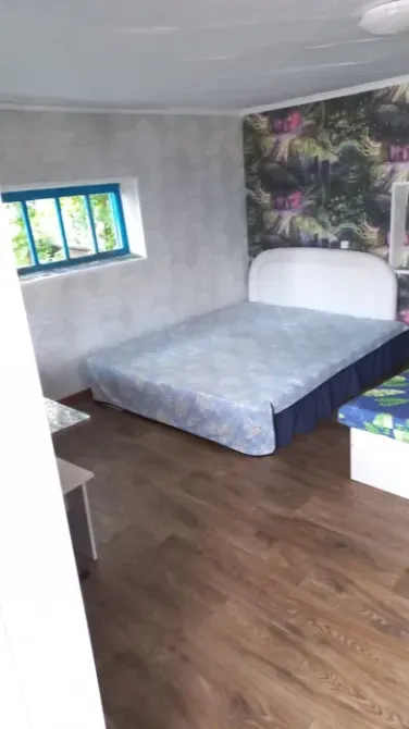 Комната с двуспальной кроватью и зелеными элементами, большое окно и чистая окружающая обстановка