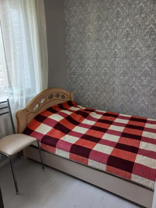 Спальня с односпальной кроватью, оформленная в красно-белую клетку, рядом стул