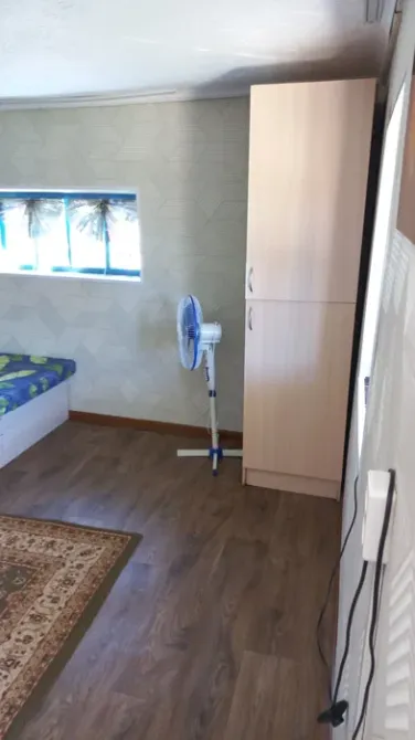 Комната с кроватью, вентилятором и шкафом, оформленная в нейтральных тонах