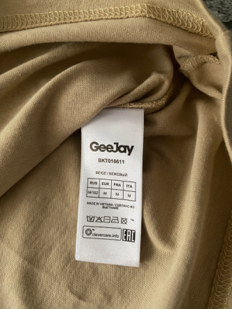 Футболка бежевого цвета на плоской поверхности