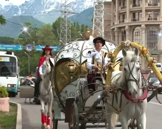 Свадебная пара стоит на ступенях, позирующая для фотографии на фоне кареты с лошадью