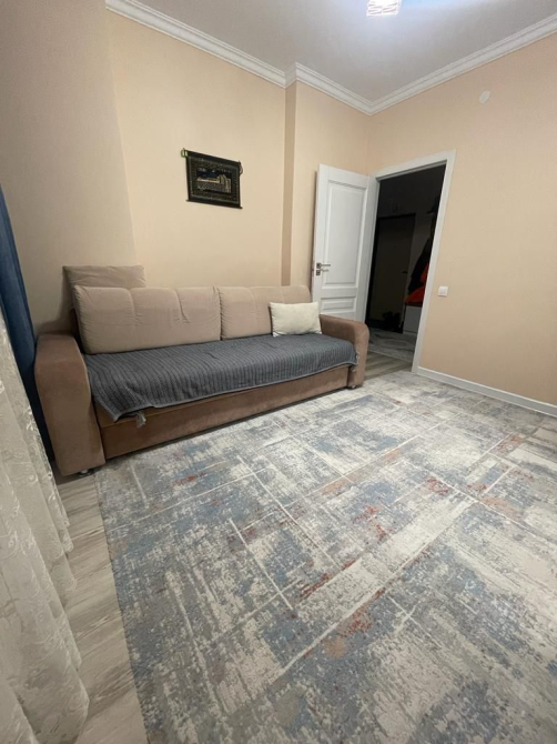 Светлая комната с диваном, ковром и открытой дверью