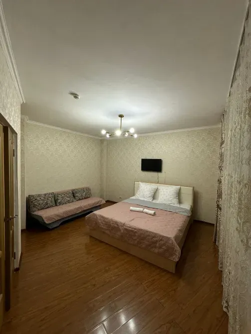 Спальня с кроватью, диваном и телевизором на стене