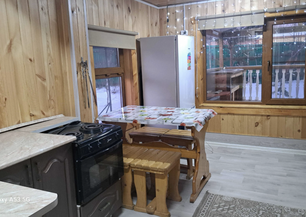 Кухня в деревянном оформлении с обеденным столом и плитой