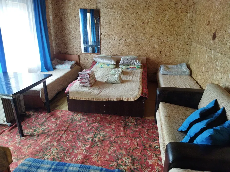 Спальня с диваном, двумя кроватями и зеркалом, оформленная в теплых тонах