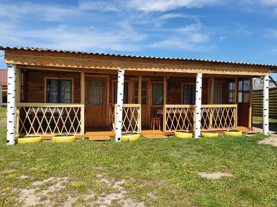 Деревянный домик с верандой и зелёным двором