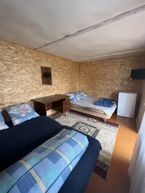 Комната с двумя кроватями, телевизором и холодильником