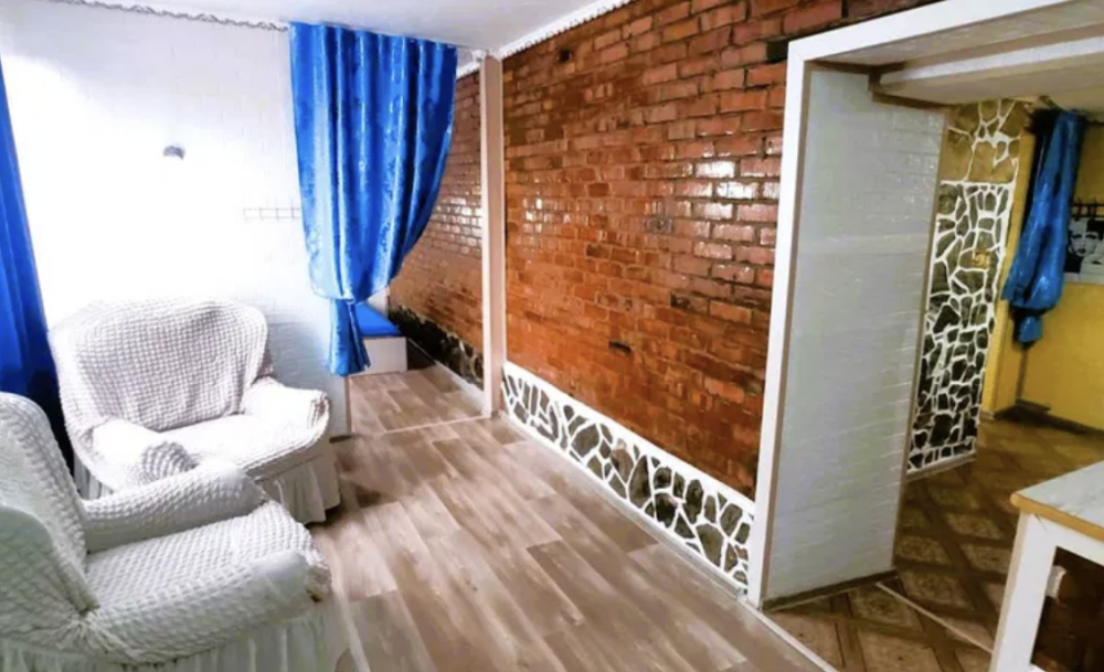 Уютная гостиная с белым диваном и кирпичной стеной