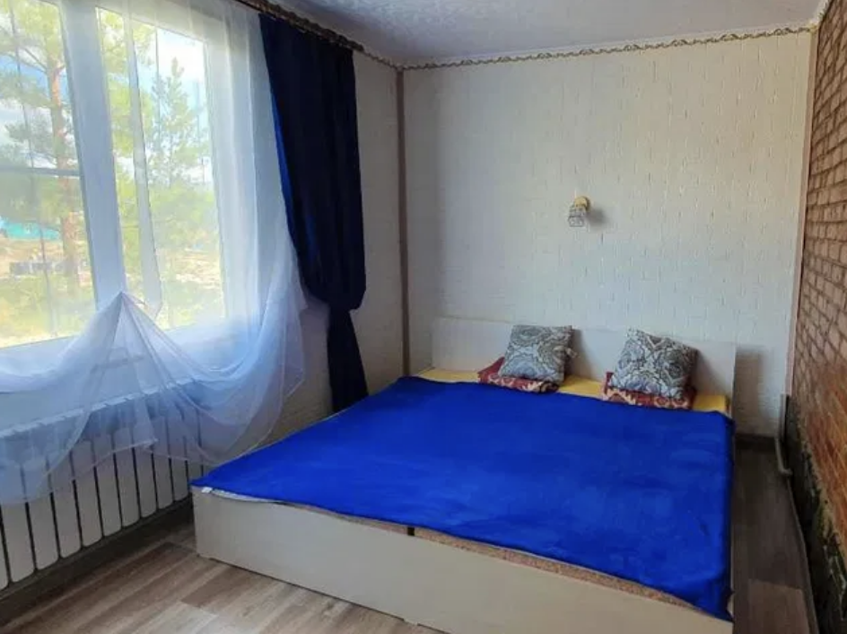 Спальная комната с синей простыней и двумя подушками