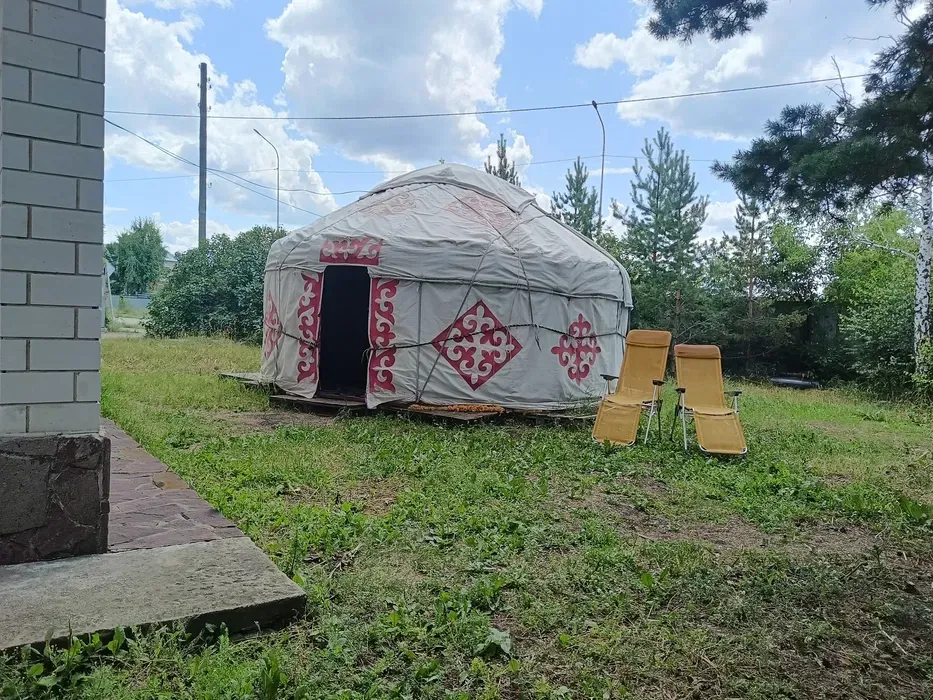 Юрта на зеленом участке с пляжными креслами
