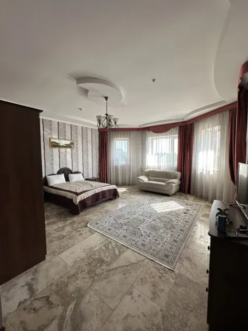 Комната с двуспальной кроватью и диваном, оформленная в светлых тонах