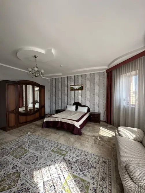 Вторая спальня с двуспальной кроватью и зеркальным шкафом, оформленная в стиле | Красивый вид на горы и зелёные поля из окна