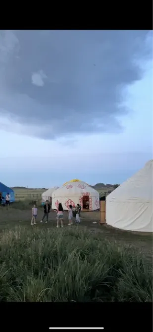 Группа людей возле юрт под облаками