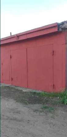 Красная стена здания с закрытыми дверями на фоне неба