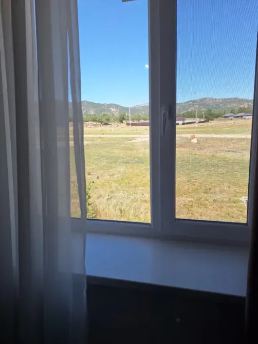 Вид из окна на участок с зелеными холмами