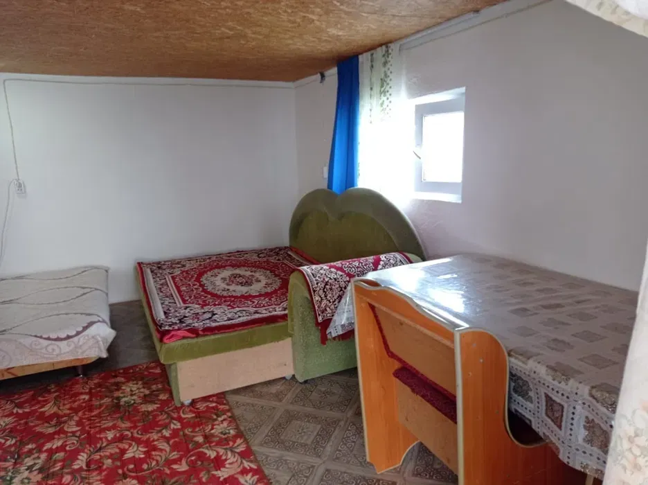 Комната с двумя кроватями и столом, декорирована красным ковром