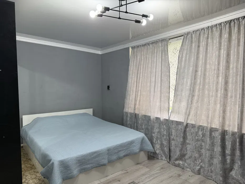 Спальня с двуспальной кроватью и светлыми шторами