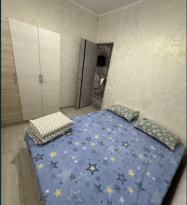 Спальня с двуспальной кроватью и текстильными принадлежностями, оформленная в светлых тонах