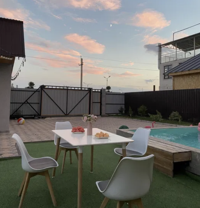 Уютный столик на улице с видом на сад и бассейн под красивым небом