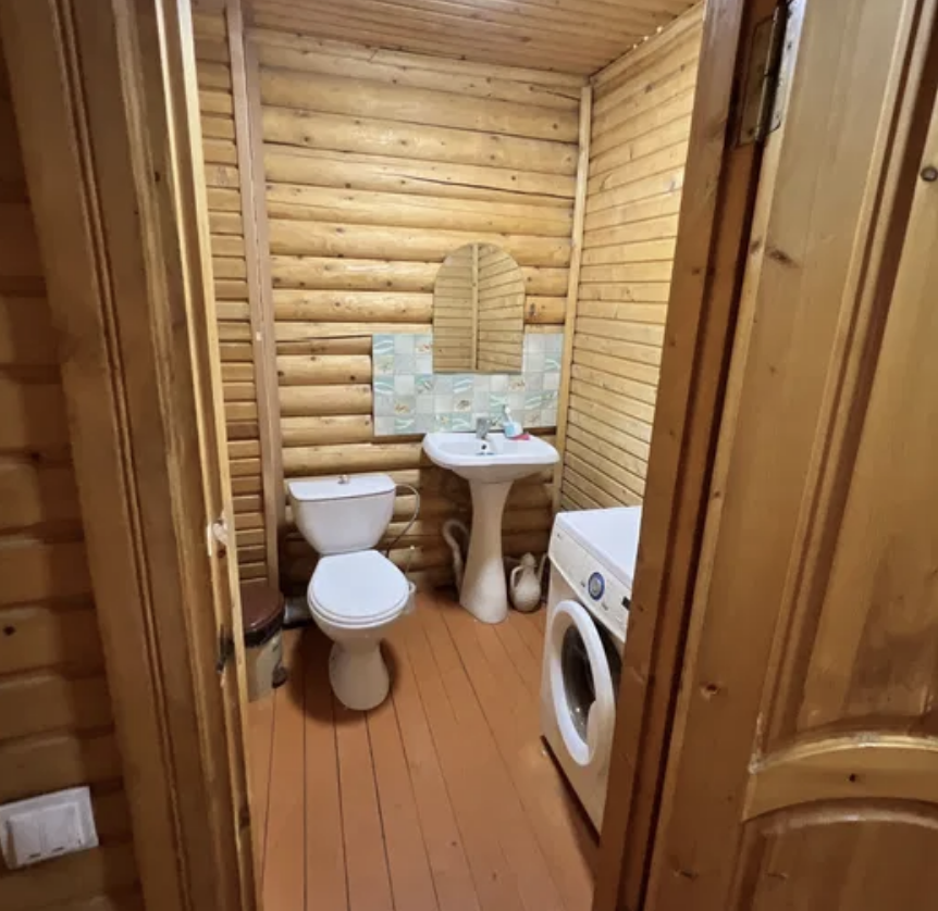 Ағаш үйдегі унитаз және кір жуғыш машинасы бар ванна бөлмесі