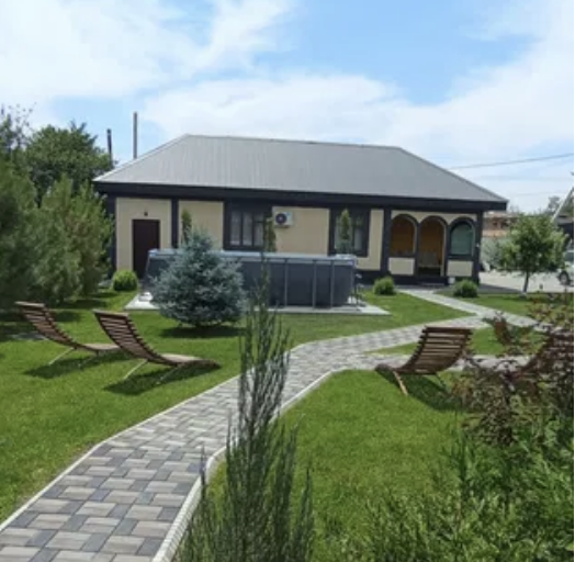 жасыл бақша мен екі шезлонгі бар үй