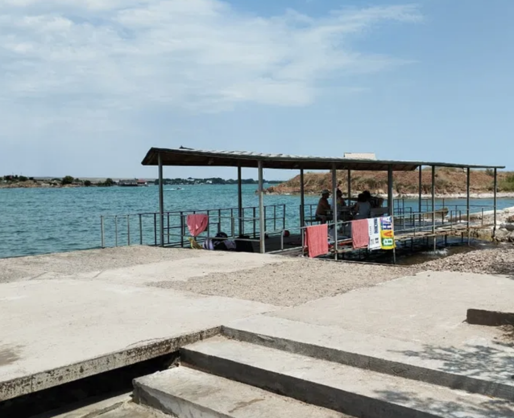 Пристань у воды с отдыхающими на берегу