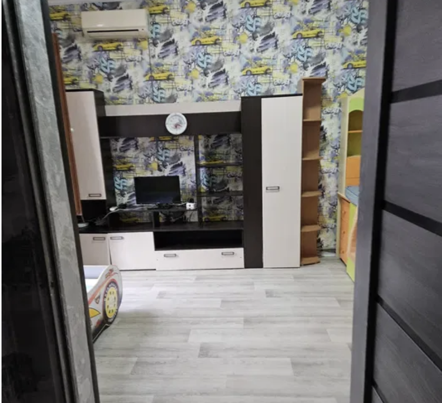 Вторая комната с яркими обоями, телевизором и шкафом для игрушек