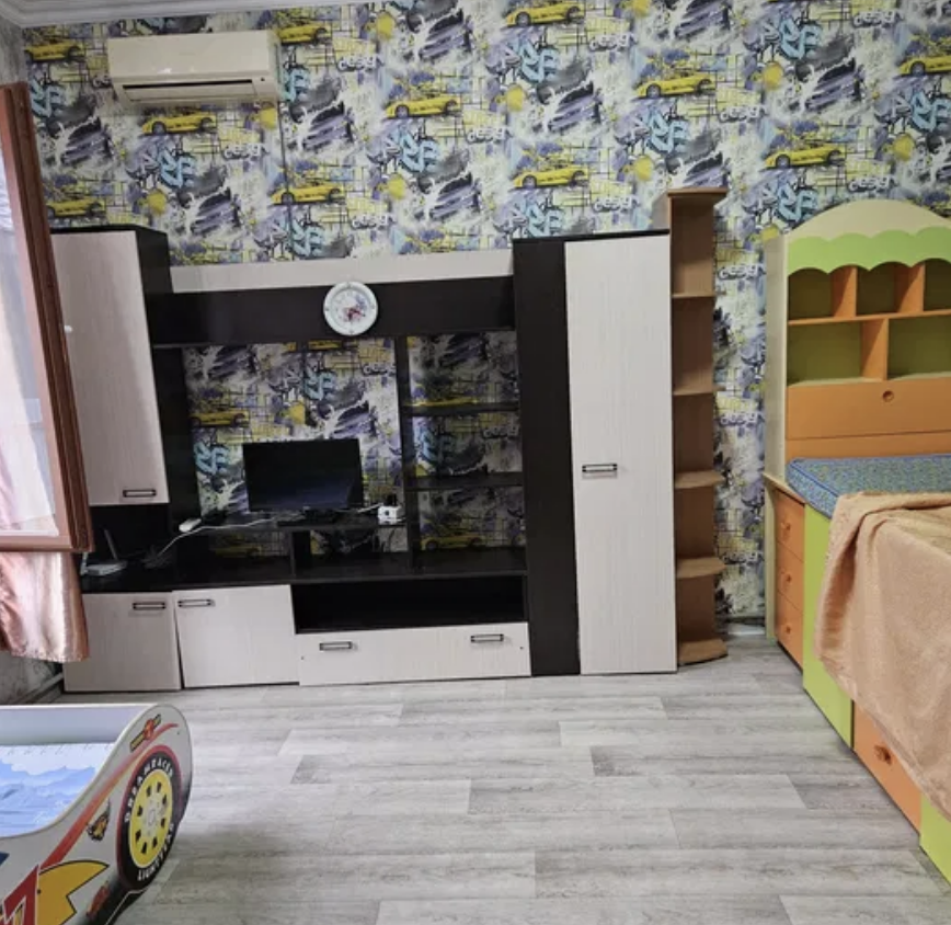 Комната с яркими обоями, мебелью для хранения и кроватью, компьютерным столом