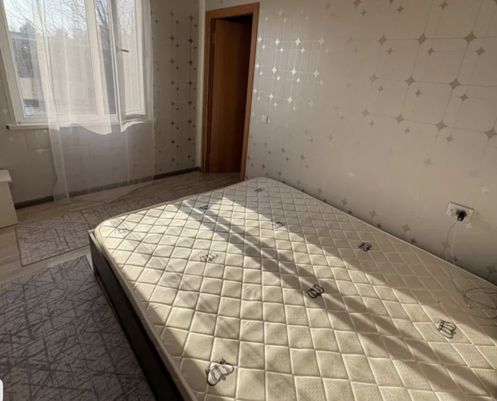 Спальня с пустой кроватью и солнечным светом, проникающим через окно