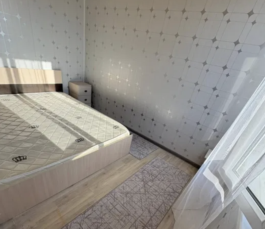 Спальня с кроватью, касающейся стены, и небольшим прикроватным столиком