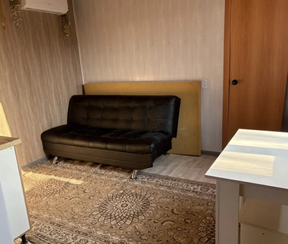 Уютный уголок с черным диваном и светлым ковром на полу