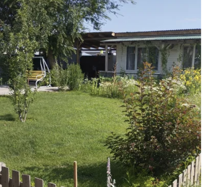 Участок с ухоженной зеленой травой и цветами, деревянный забор