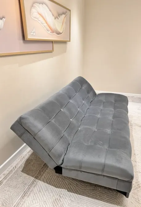 Диван серого цвета, расположенный у стены, с подушками и элегантным дизайном