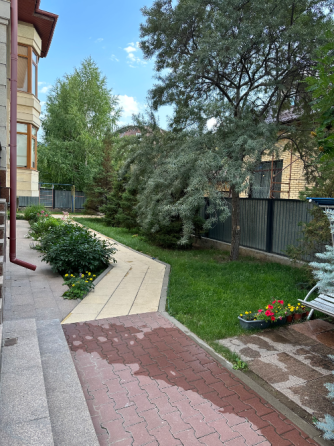 Участок с ухоженным газоном и дорожками, окружённый деревьями и кустарниками